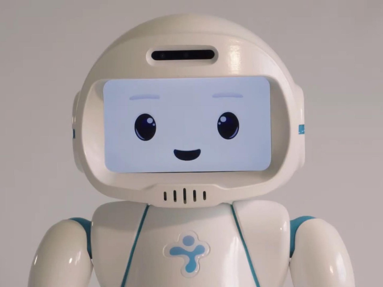 QTrobot de LuxAI, avec son visage souriant sur écran et ses épaules turquoise.
